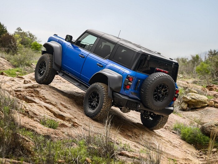 Blue Ford Bronco driving up the rocks